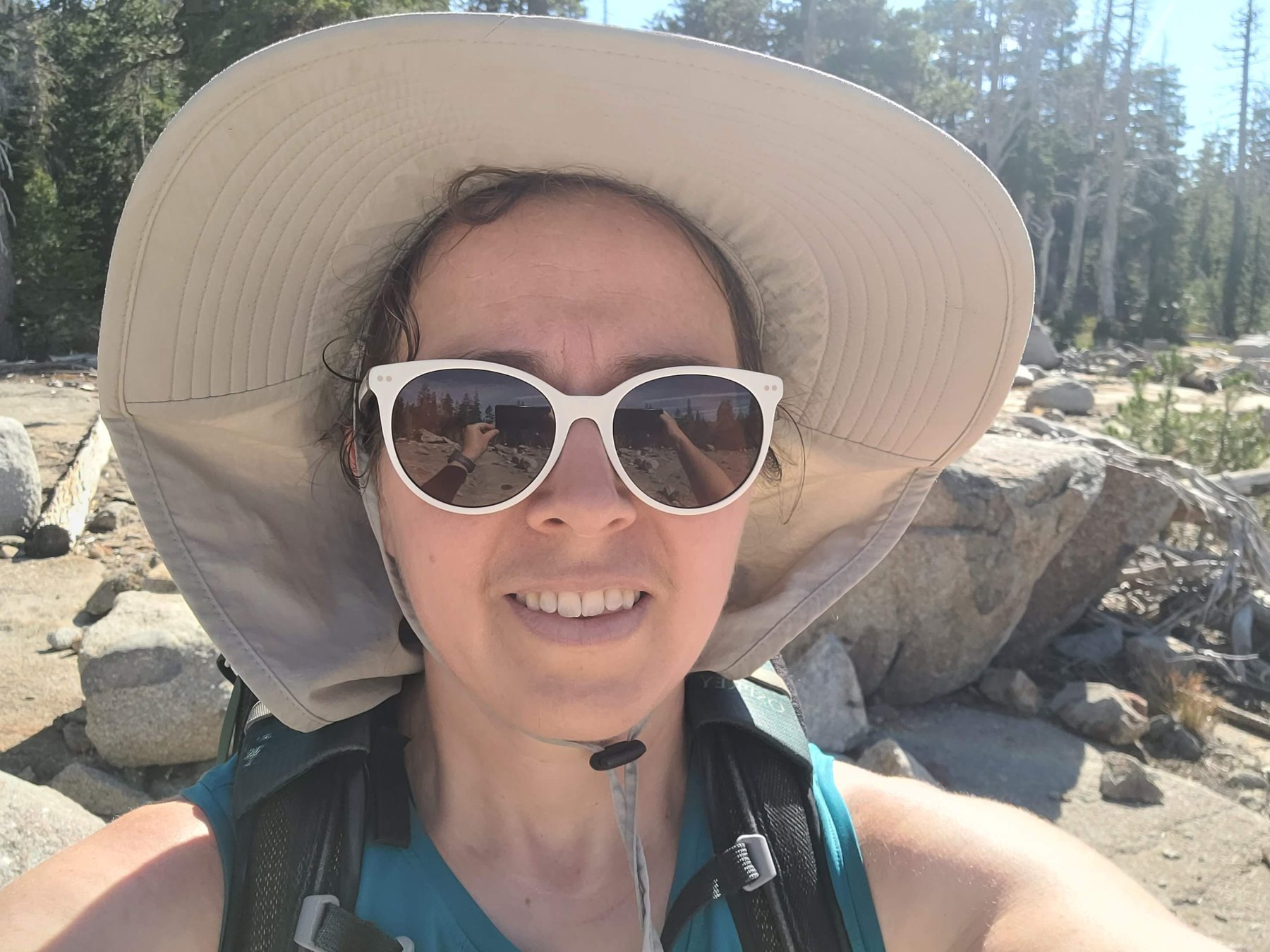 Esther wearing a sun hat and sunglasses on her backpacking trip